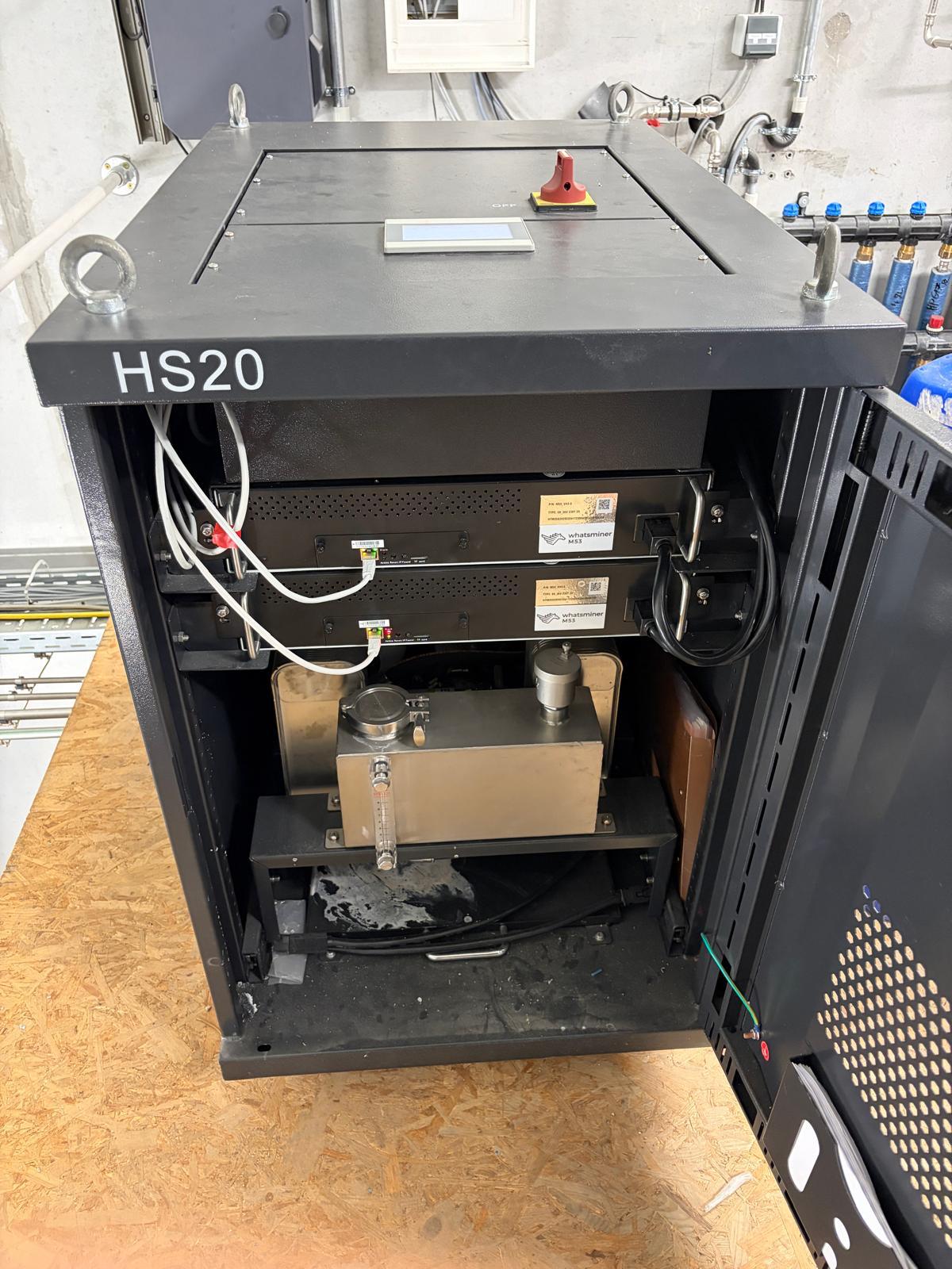 Geöffneter Schrank – zwei Whatsminer M53 Hydro über dem Wärmetauscher